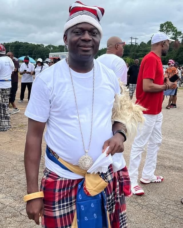 Man in cultural attire standing in front of people.